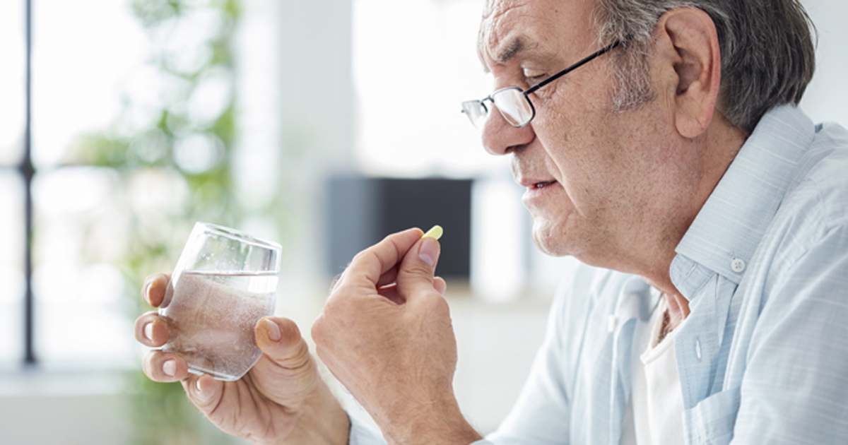 Old man taking pill